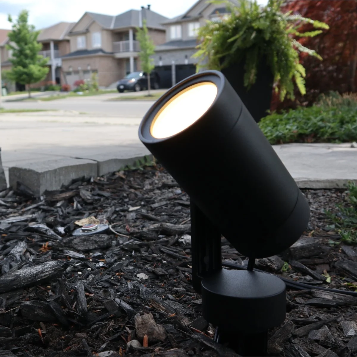 Black Hampton Bay spotlight in mulch lighting a house in Ancaster