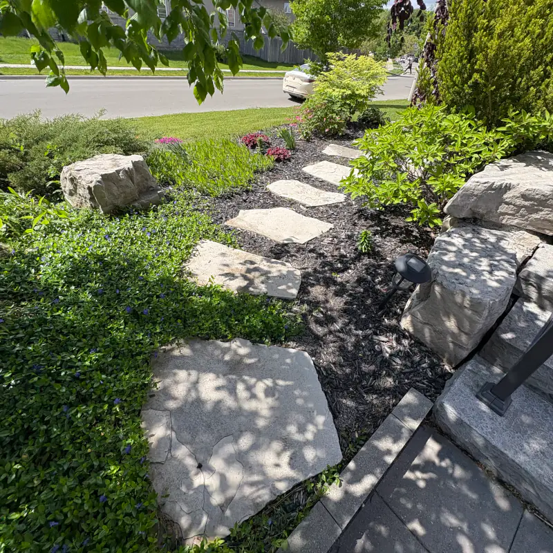 Natural stone step walkway with lush perimeter plantings creating a sense of enclosure in Ancaster