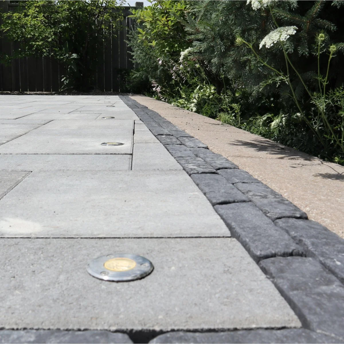 Patio of Permacon Melville paver and a Unilock Copthorne sailor course border with embedded landscape light in Hamilton